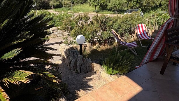 A patio with a view of a garden, a hammock, and a flag. - Holiday Home 'Appartamento Baia 12' with Private Garden, Wi-Fi and Air Conditioning (Baia Vignola)
