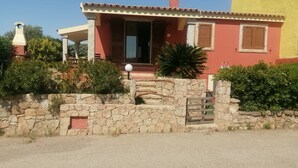 A two-story house with a stone wall entrance, a porch with a lamp, and a window with shutters. - Holiday Home 'Appartamento Baia 12' with Private Garden, Wi-Fi and Air Conditioning (Baia Vignola)
