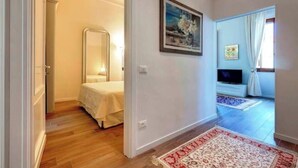 Una stanza con un letto, uno specchio, un quadro, una televisione e un tappeto a motivi.