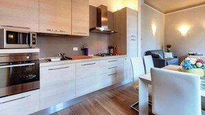 Una cucina moderna con elettrodomestici in acciaio inossidabile, mobili in legno e un'area pranzo con tavolo e sedie.