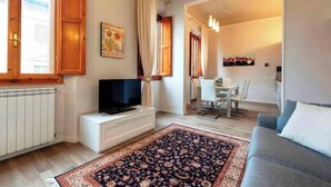 Un soggiorno con televisione, una zona pranzo con tavolo e sedie, e un divano.