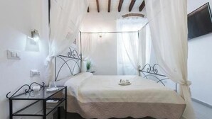 A bedroom with a bed, a bedside table, a TV on the wall, and a window with curtains. - Little Box House - Modern design and tranquility in the heart of the city (Firenze)