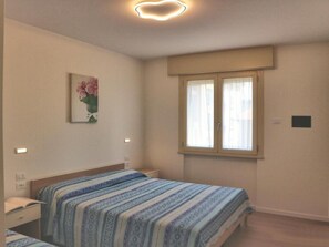Una camera da letto con un letto, un comodino e una finestra con tende.