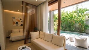 Et moderne soveværelse med en sofa, en seng, et lille bord og udsigt til en pool.
