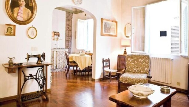 A room with a sewing machine, a dining table with chairs, a patterned armchair, and a radiator. - An authentic stay in the heart of Florence, a stone's throw from history (Firenze)