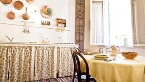 A dining area with a table set for two, a patterned curtain, and a window with curtains. - An authentic stay in the heart of Florence, a stone's throw from history (Firenze)