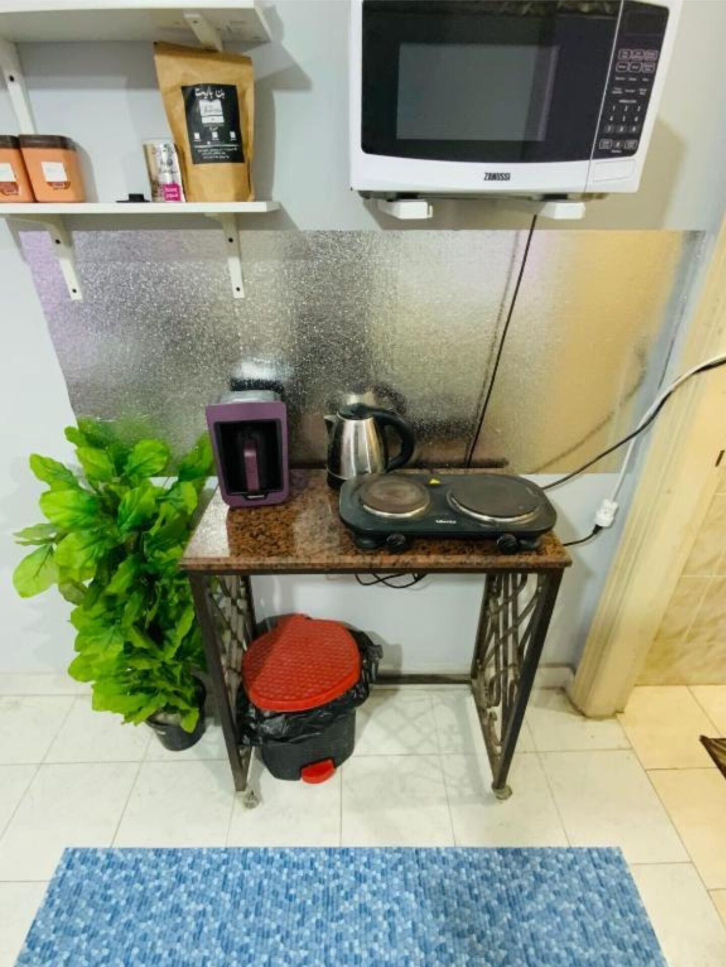 A compact kitchenette with a microwave, coffee maker, and kettle on a small table.