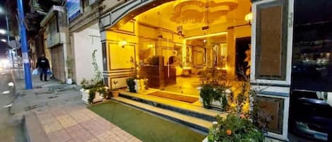 A hotel entrance with a welcoming archway, a small outdoor pool, and potted plants.