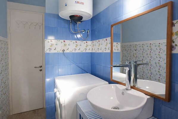 A bathroom with a white sink, a mirror, and a wall-mounted heater.