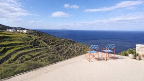 Eine Terrasse mit Stühlen mit Blick auf eine Küstenlandschaft.