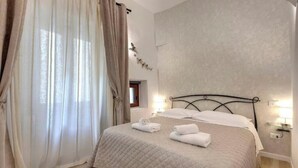 Une chambre à coucher avec un lit, des rideaux, une table de chevet et des lampes fixées au mur.