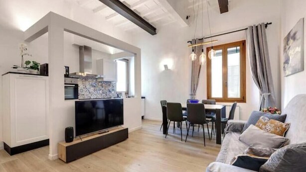 Un salon moderne doté d’un téléviseur à écran plat, d’un coin repas avec des chaises et d’un canapé.