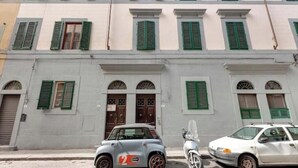 Un bâtiment doté de nombreuses fenêtres et portes, une voiture garée et un scooter.
