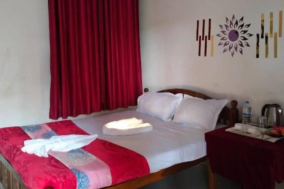 A bed with a wooden frame, a red and white bedspread, a white pillow, and a bedside table with a red cloth.
