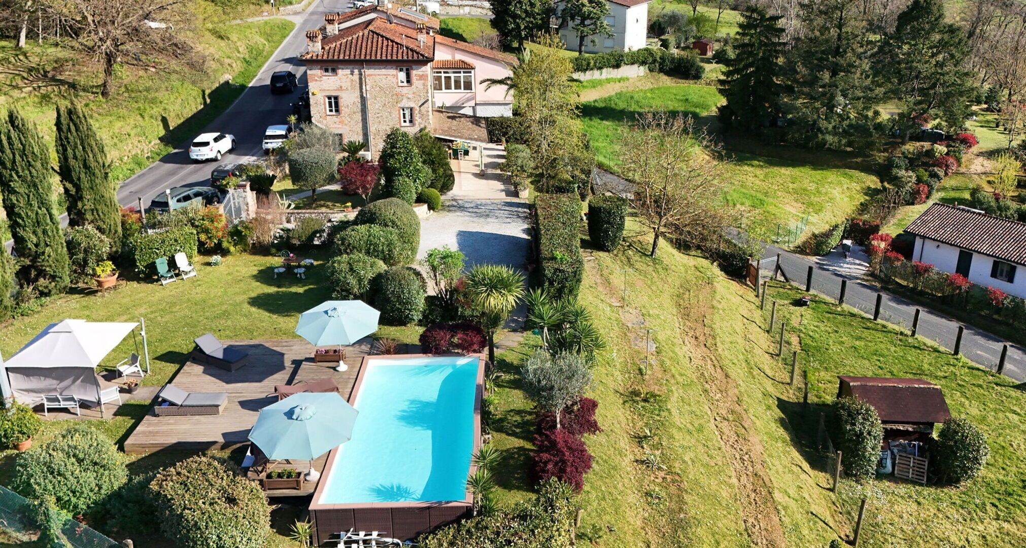 A residential property with a swimming pool, a driveway, and a garden.