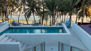 A swimming pool with steps leading down to the water, surrounded by palm trees and a beach view. - Ramada Encore by Wyndham Boracay White Beach (Boracay Island)