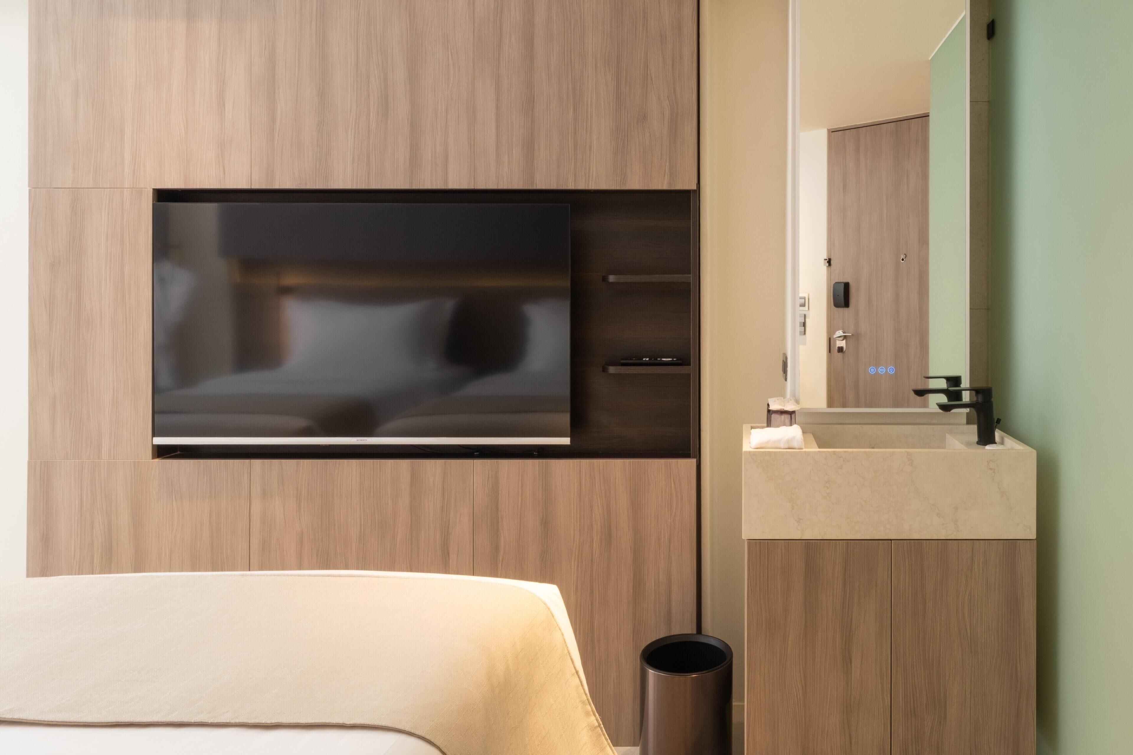 A modern bathroom with a built-in TV, a sink, and a mirror.