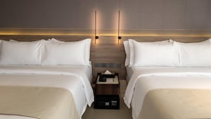 A hotel room with two beds, a nightstand, and a wall-mounted light fixture. - Ramada Encore by Wyndham Boracay White Beach (Boracay Island)