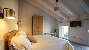A bedroom with a bed, a wooden wardrobe, a bedside table, a TV mounted on the wall, and a window. - Elegant House with Swimming Pool and Large Green Garden (Veneto)