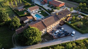 An aerial view of a large building with multiple sections, including a swimming pool, parking area, and adjacent green spaces. - Elegant House with Swimming Pool and Large Green Garden (Veneto)
