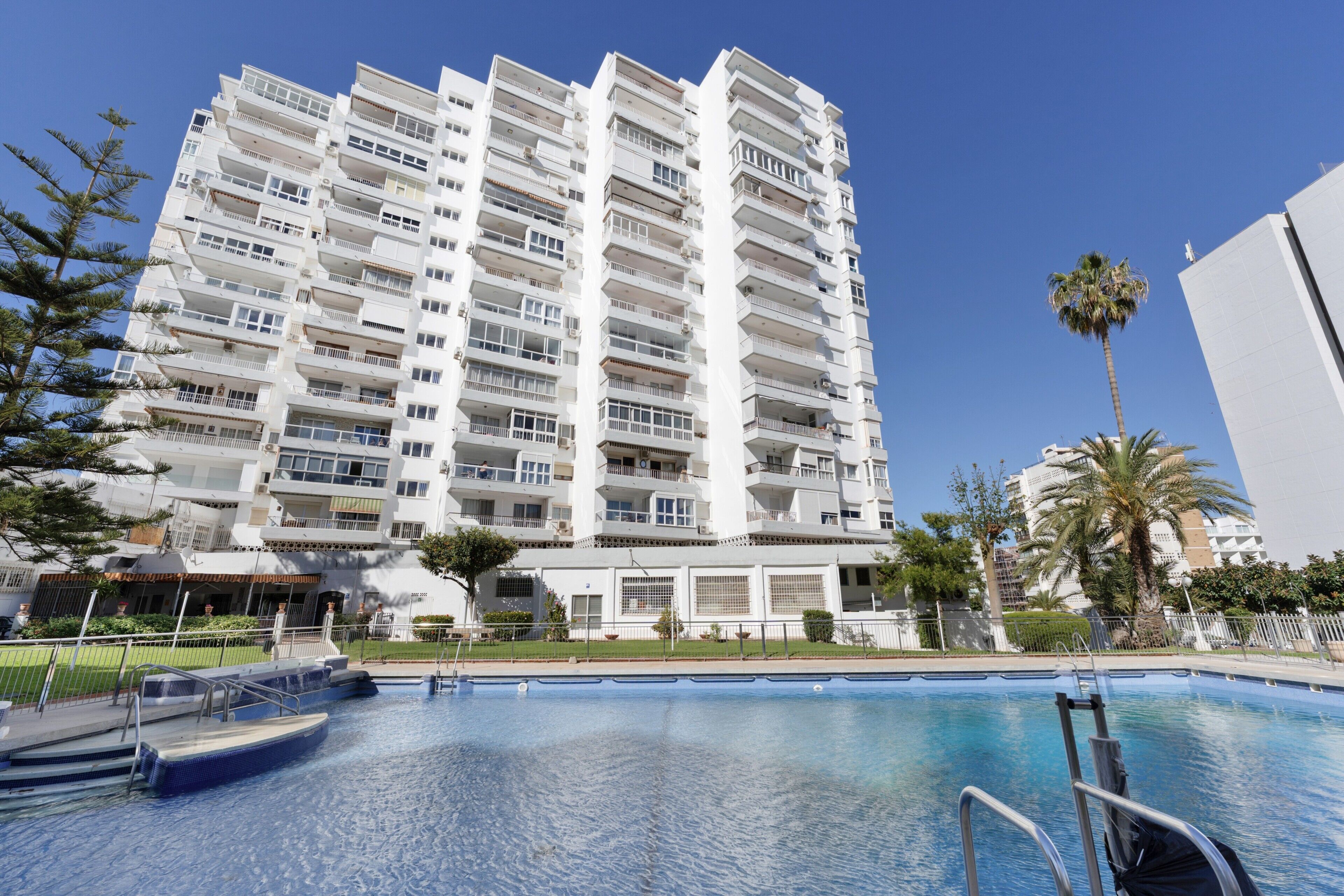 A high-rise building with a swimming pool in front.