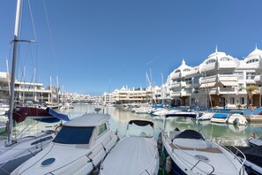 A marina with multiple boats docked, a clear blue sky, and buildings with distinctive architecture in the background. - Apartment 'En Benalmádena 402' with Sea Views, Wi-Fi and Air Conditioning (Benalmádena)