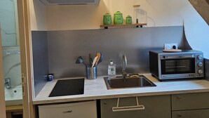 Kompakti keittiö, jossa on sisäänrakennettu mikroaaltouuni, pesuallas ja pieni työtaso.