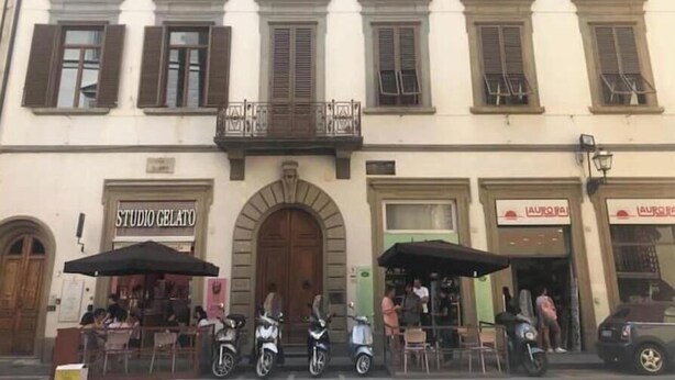 A building with multiple storefronts, including a visible restaurant named 'STUDIO GELATO' and a shop with signage in a foreign language. - Bsddfffffffff (Firenze)