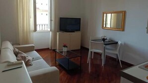 A living room with a sofa, a TV on a cabinet, a small table, and a chair. - Bsddfffffffff (Firenze)