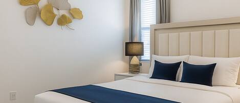 A bedroom with a bed, bedside tables, a lamp, and wall decorations.