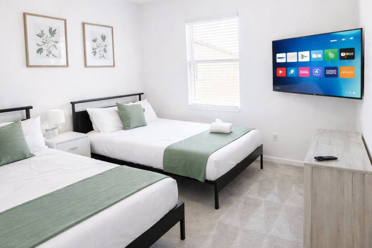 Une chambre d’hôtel avec deux lits, une télévision, un bureau et une fenêtre.
