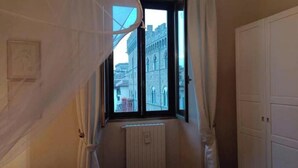 Een smalle gang met een raam, een radiator en een deur.