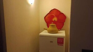 Een kleine witte koelkast met een rode bloemdecoratie bovenop en een waarschuwing.