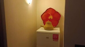 Ein kleiner, weißer Kühlschrank mit roter Blütenverzierung auf der Oberseite und einer Warnhinweistafel.