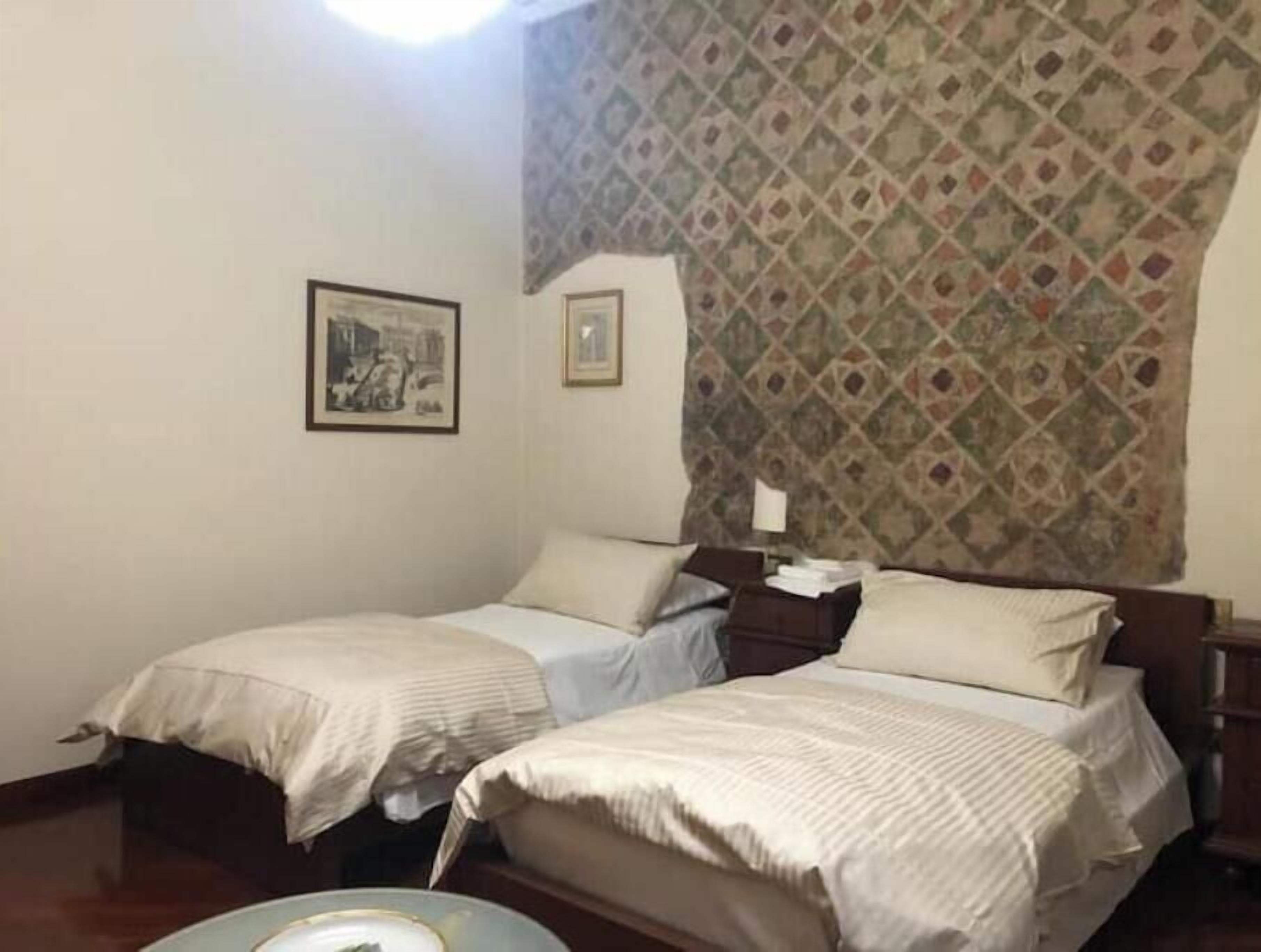 Une chambre avec deux lits, un mur décoré d’un motif et deux tableaux encadrés.