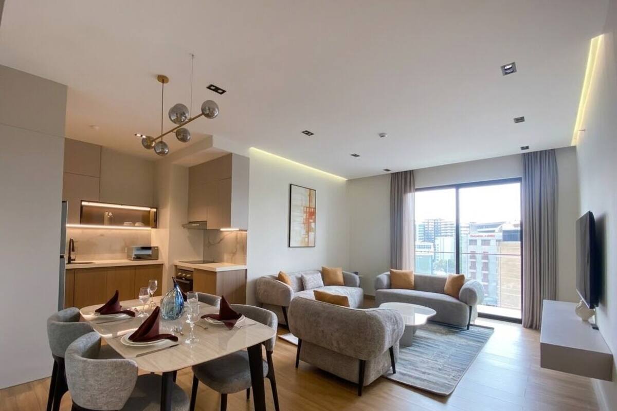A modern living room with a dining area, a kitchen, and a large window with a view.