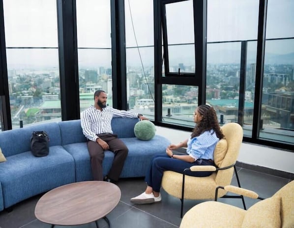 A modern interior with a large window, a blue sofa, a round table, and a chair.