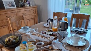 A breakfast table set with various food items, a coffee maker, and a kettle.