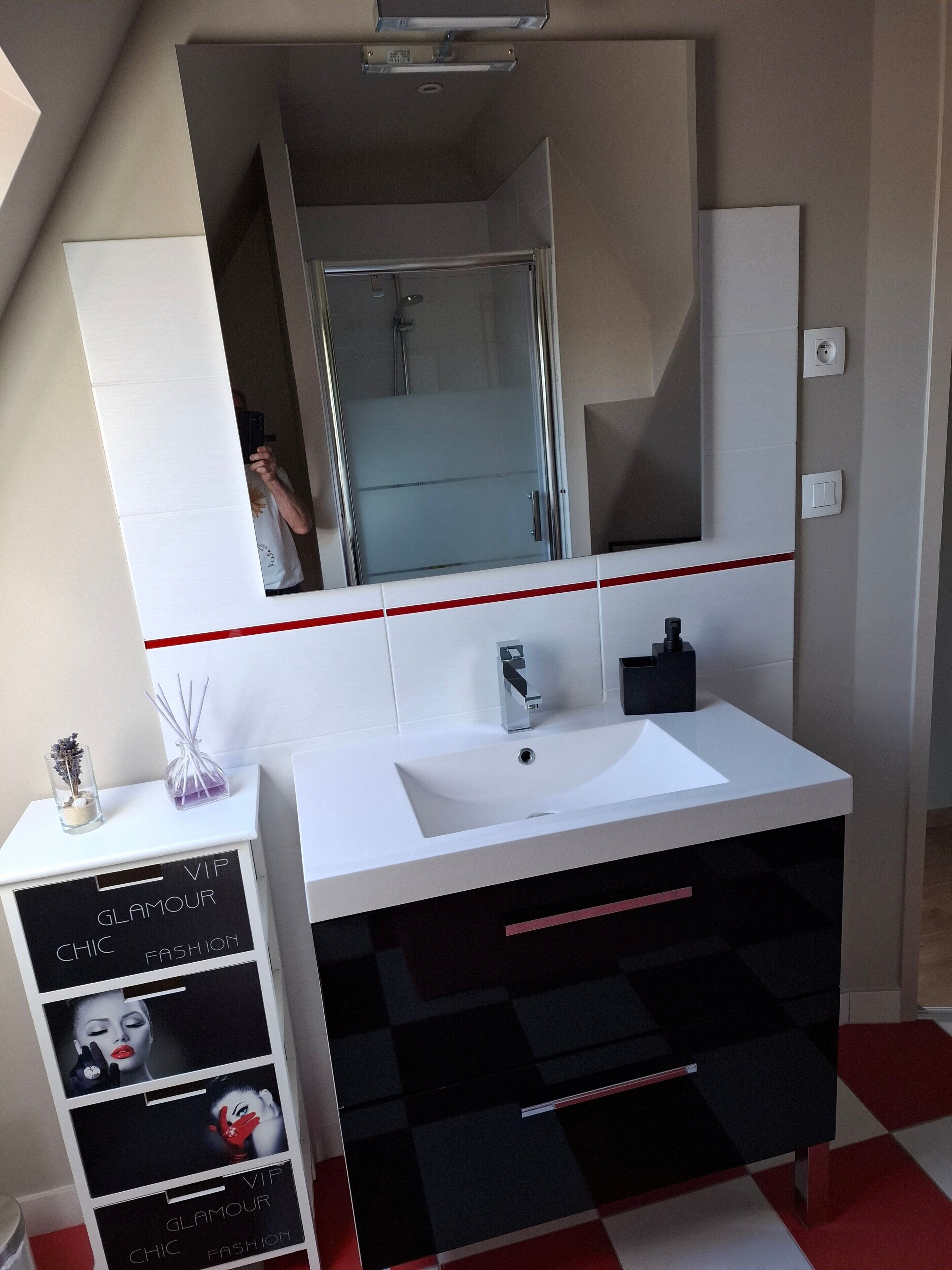 Un baño moderno con un tocador blanco, un espejo grande y una ducha visible a través del vidrio.