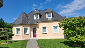 A two-story house with a red door, multiple windows, and a well-maintained lawn.