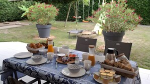 An outdoor dining area with a table set for breakfast, surrounded by potted plants and a covered patio.