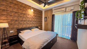 Ein Hotelzimmer mit einem Bett, einem Deckenventilator, einer Wandklimaanlage und einem Fenster mit Vorhängen.