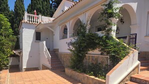 Un edificio blanco con una escalera de baldosas y un muro de piedra.