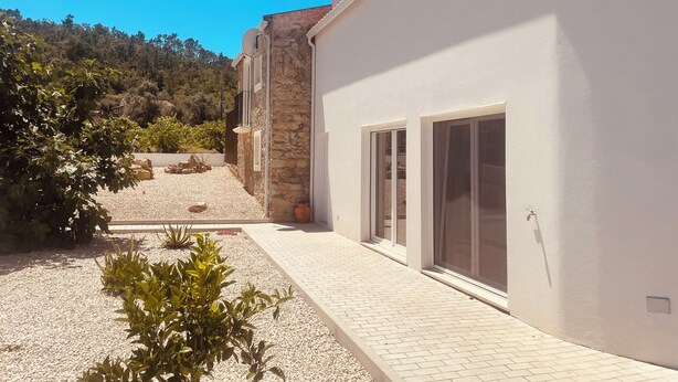 Un edificio moderno con fachada de piedra, ventanas amplias y un patio de grava.