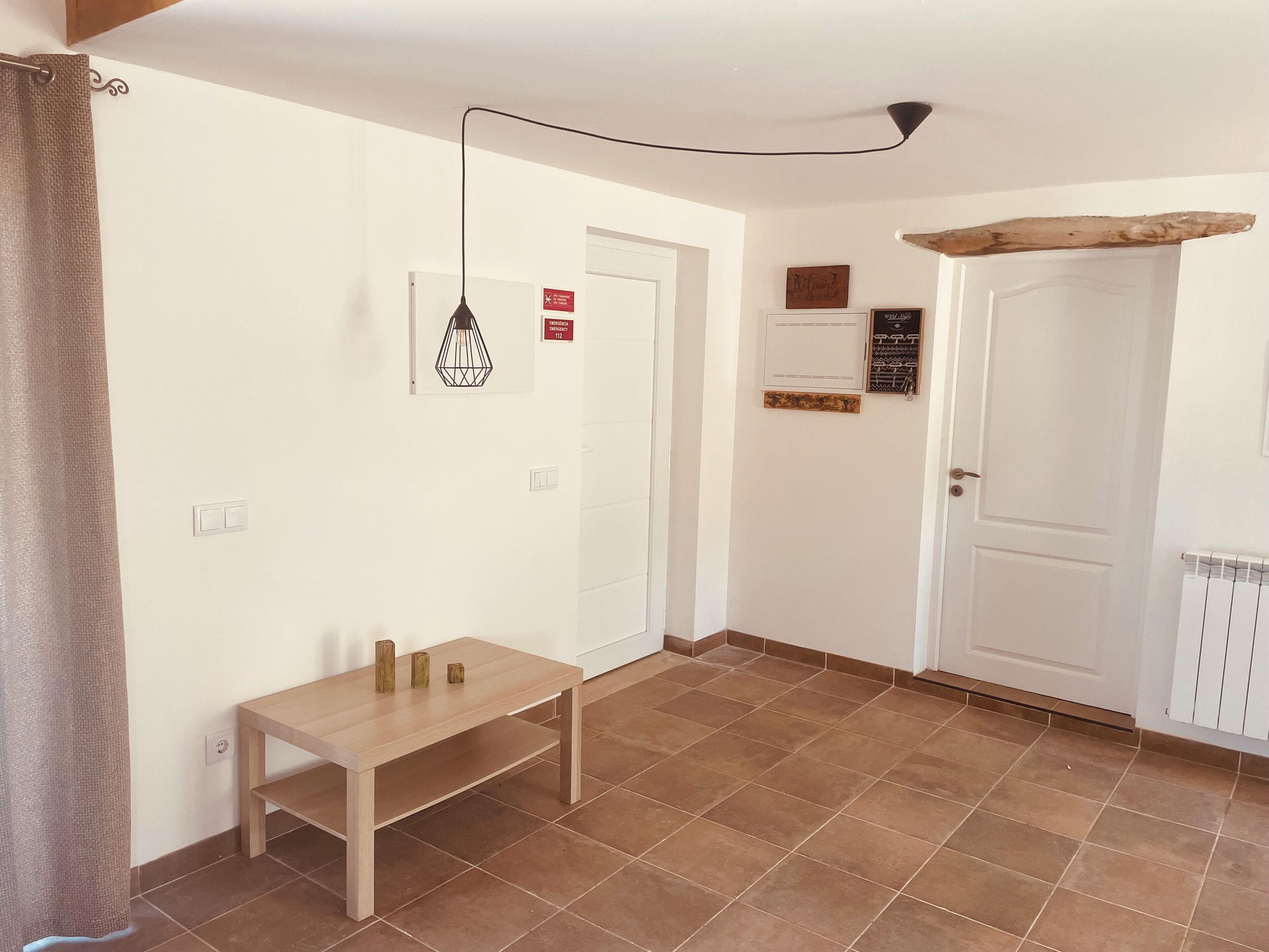 Une pièce avec une table en bois, un luminaire suspendu, une porte et un radiateur.