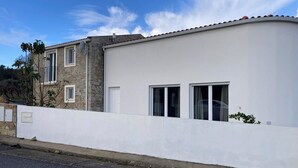 Un edificio de dos pisos con fachada blanca y una parte superior de piedra, y techo plano.
