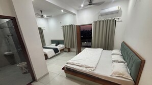 Ein Schlafzimmer mit einem großen Bett, einem Nachttisch, Vorhängen an einem Fenster und einem Deckenventilator sowie einer Klimaanlage.