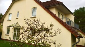 Ein zweistöckiges Haus mit Balkon, einer Tür und einem Fenster.