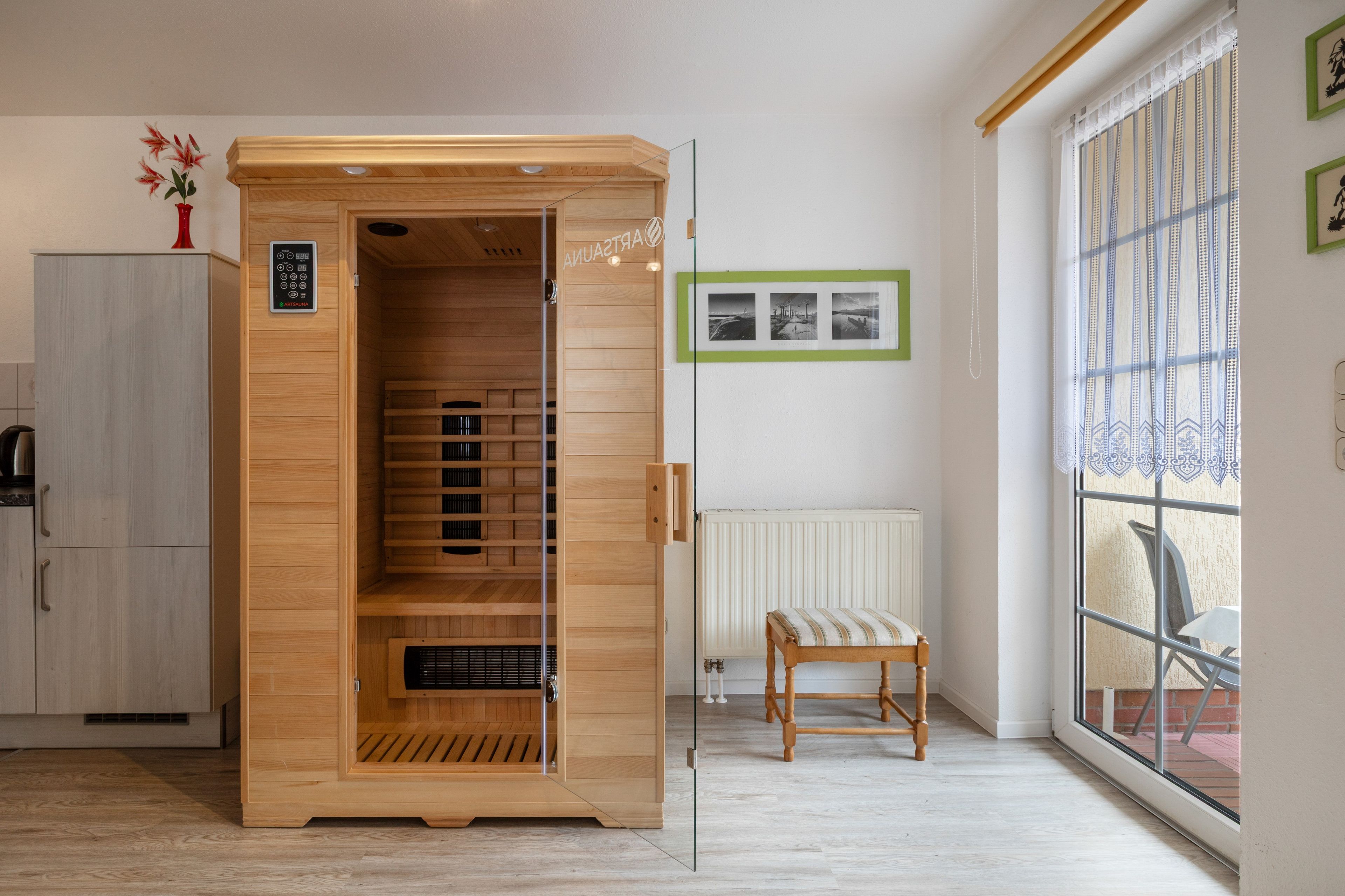 A sauna room with a wooden interior, a control panel, and a bench.