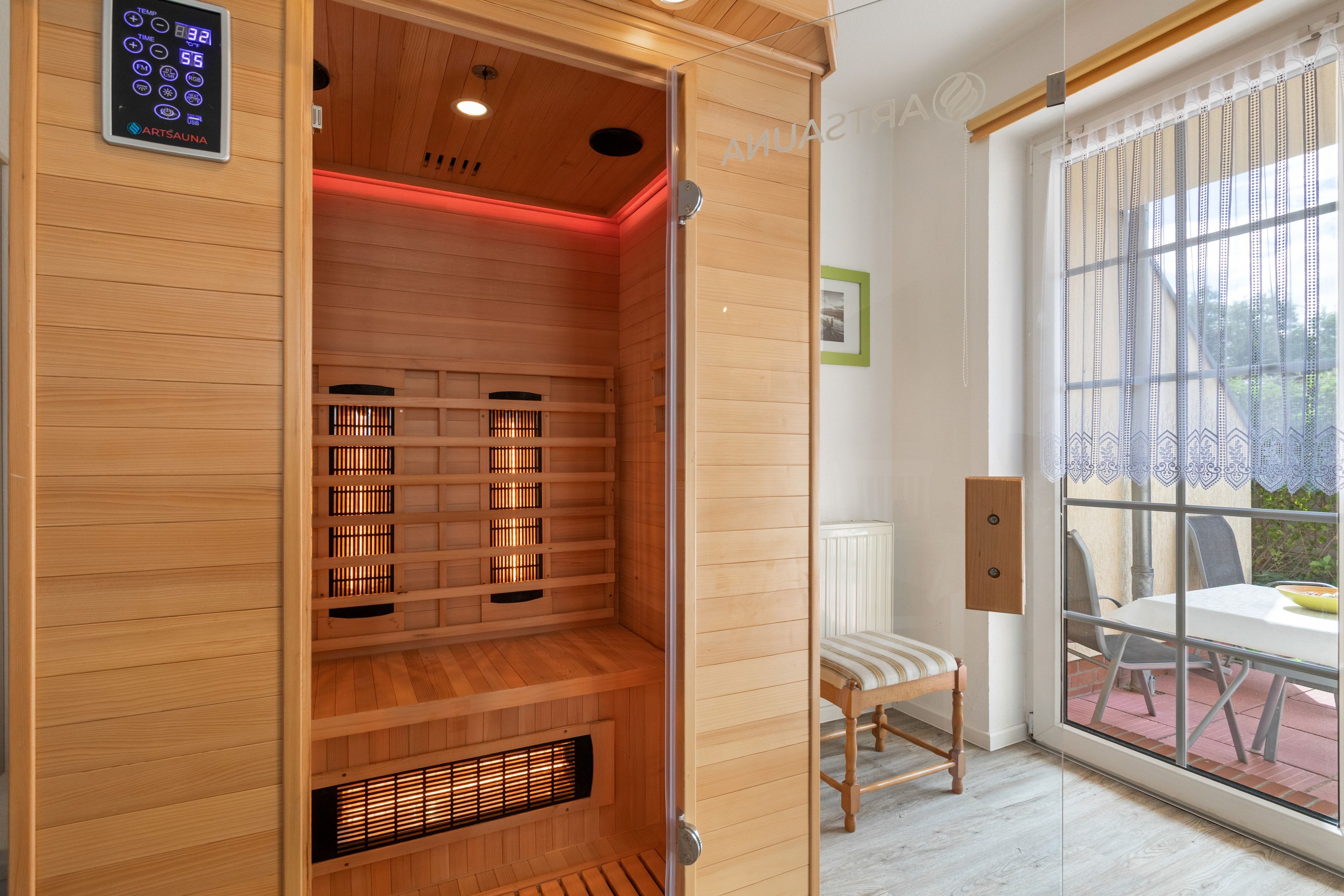 Eine Sauna mit Bedienfeld, Holzwänden und einer Sitzbank.